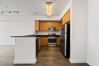 an empty apartment kitchen with black countertops and stainless steel appliances