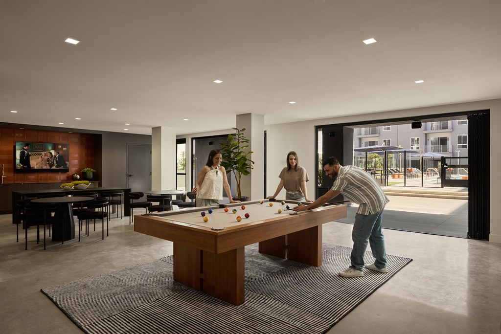 A man is playing pool in a room with a large window.