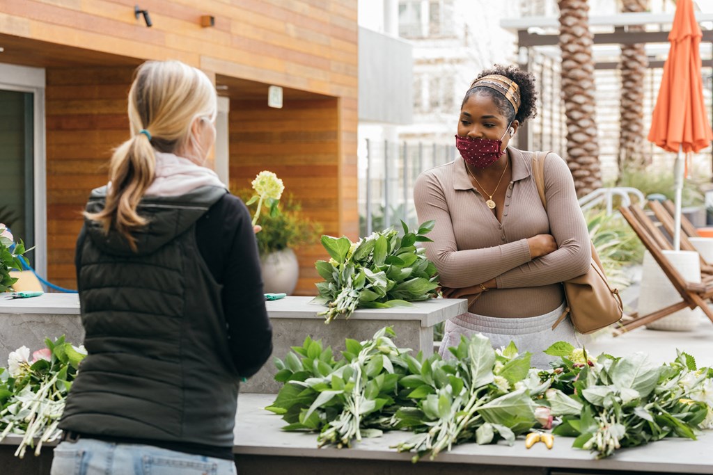 two women standing in front of a flower shop with plants