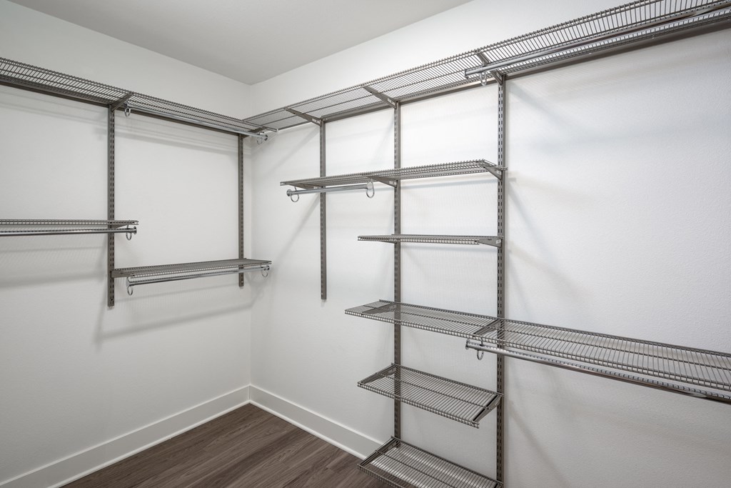 a spacious walk in closet with empty shelves and white walls