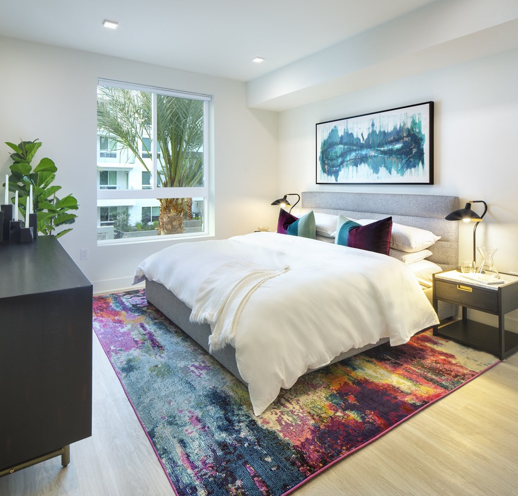 a bedroom with a bed and a rug in front of a window