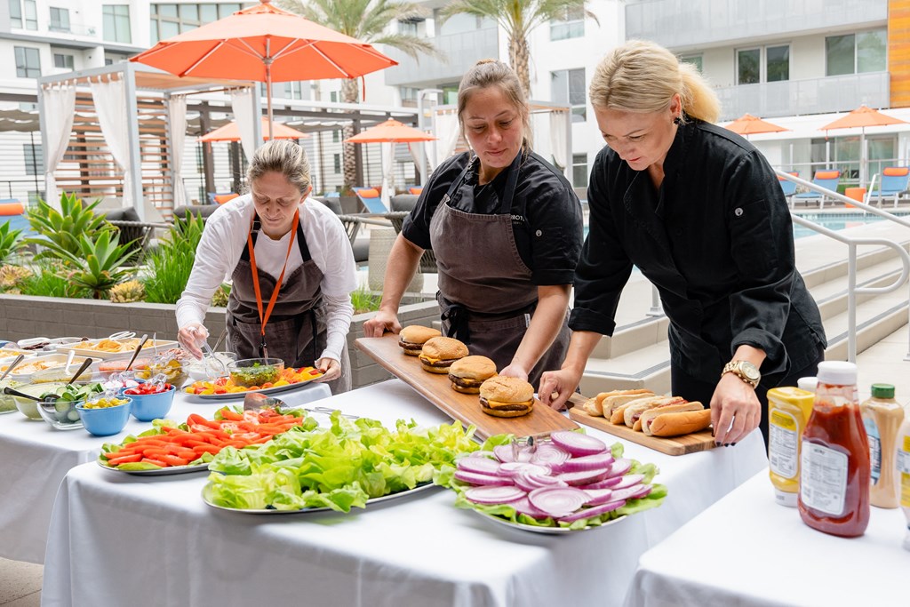 three women in aprons preparing food on a table