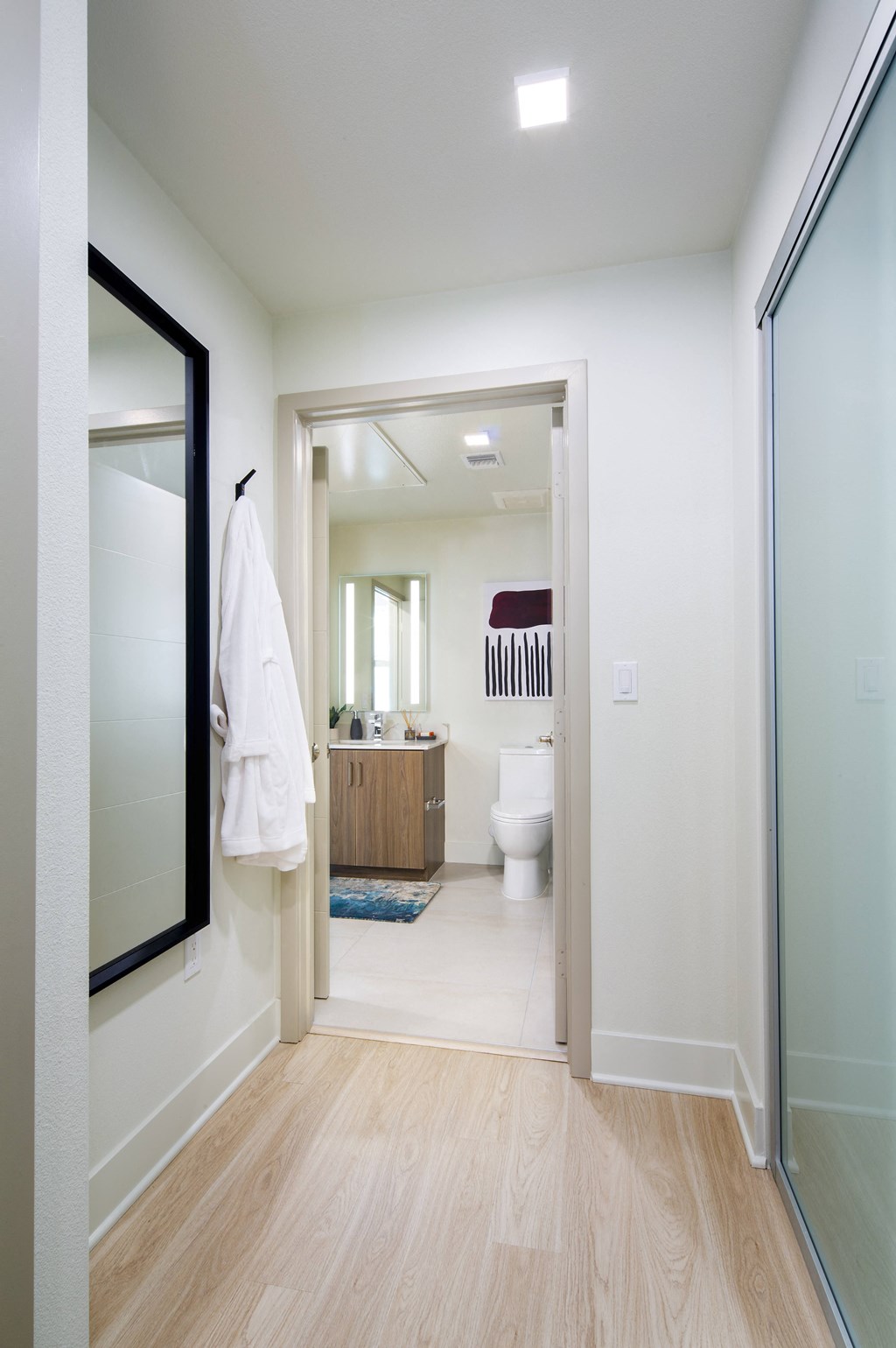 a white bathroom with a large mirror and a white toilet