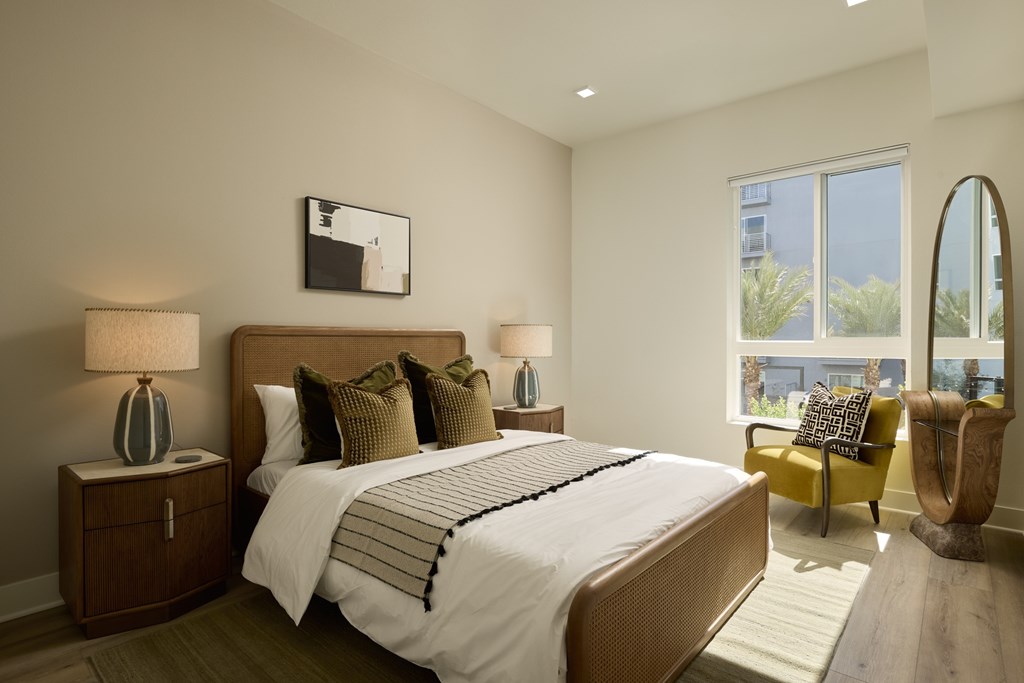 A bedroom with a large bed, two lamps, and a chair.