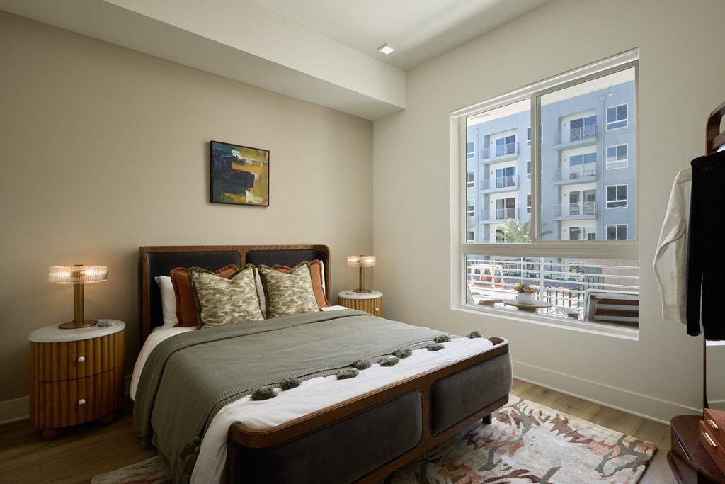 A bedroom with a large bed and a window overlooking a cityscape.