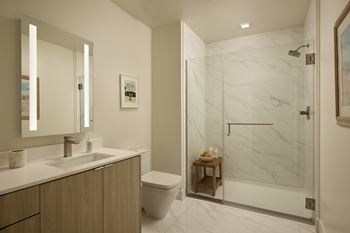 A bathroom with a marble shower and a wooden vanity.