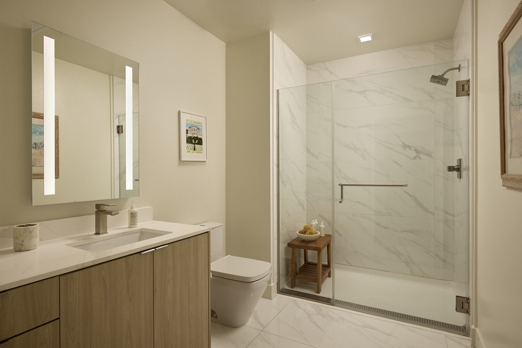 A bathroom with a marble shower and a wooden vanity.