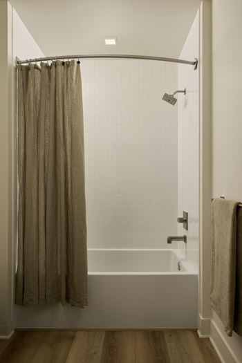 A bathroom with a shower curtain and a towel hanging on the door.