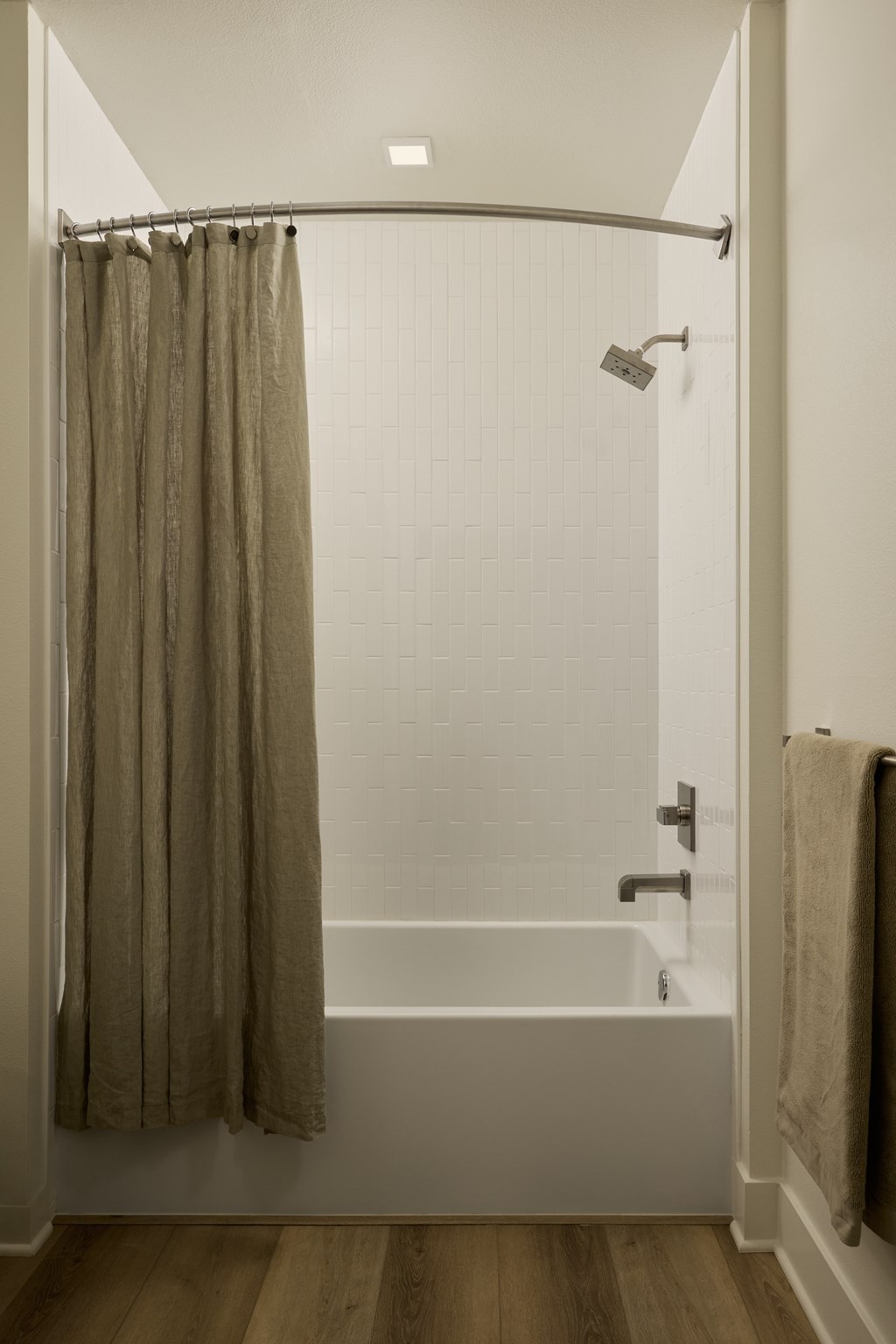 A bathroom with a shower curtain and a towel hanging on the door.