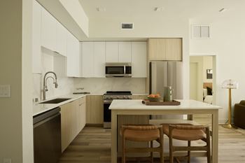 A modern kitchen with wooden chairs and a white island.