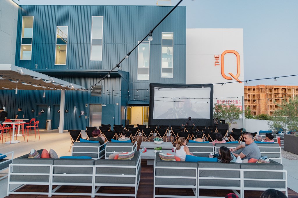 a group of children sitting on benches in front of a large screen in a building