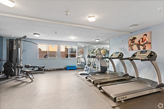 two treadmills and other exercise equipment in a gym with blue walls