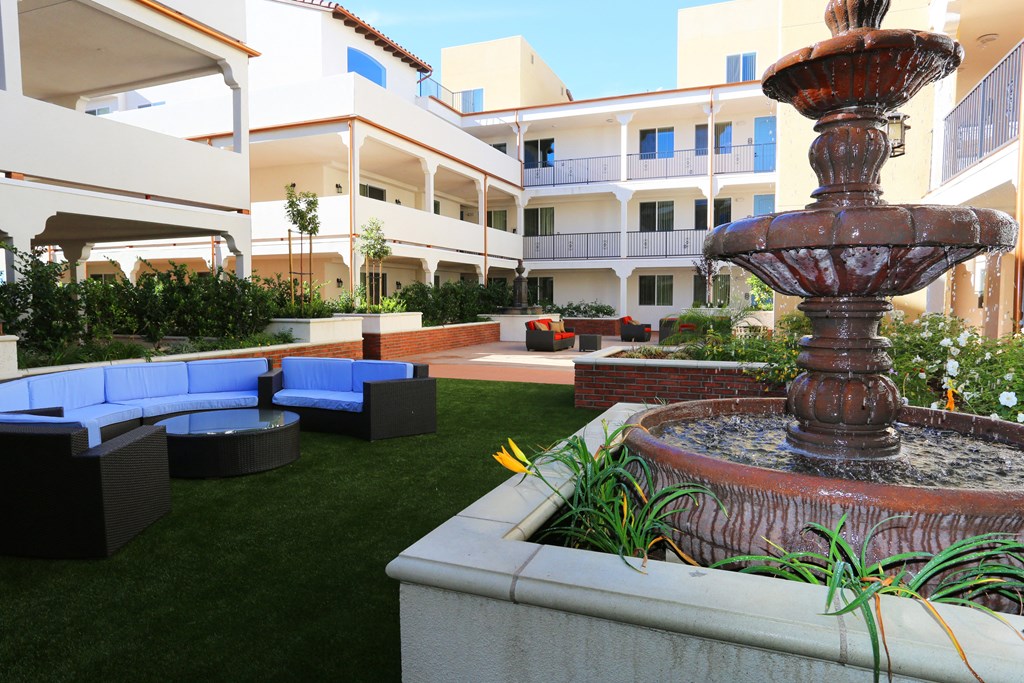 a courtyard with a fountain and blue couches in front of a building
