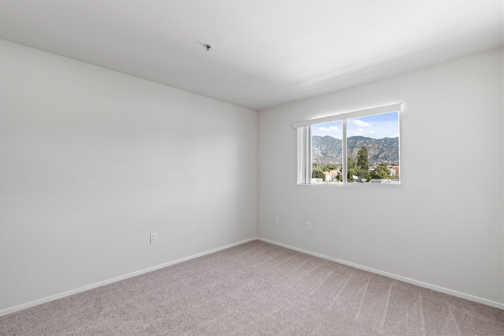 A room with a window overlooking a mountainous landscape.