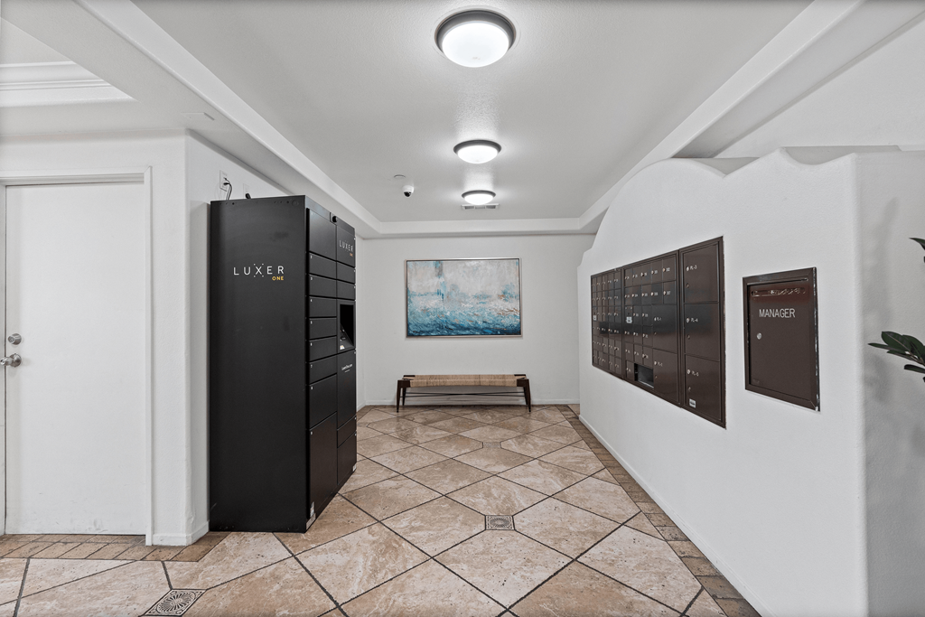 A room with a LUXE refrigerator and a painting of a beach scene on the wall.