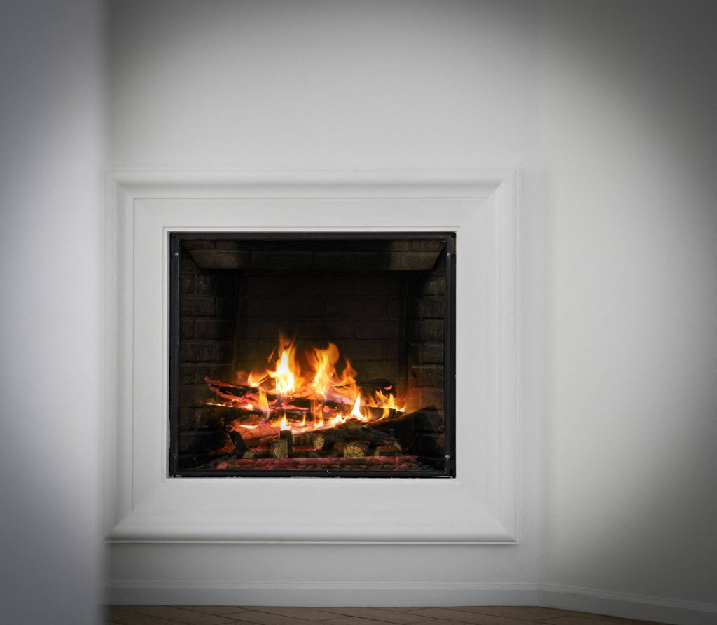 a fireplace with a roaring fire in a white room