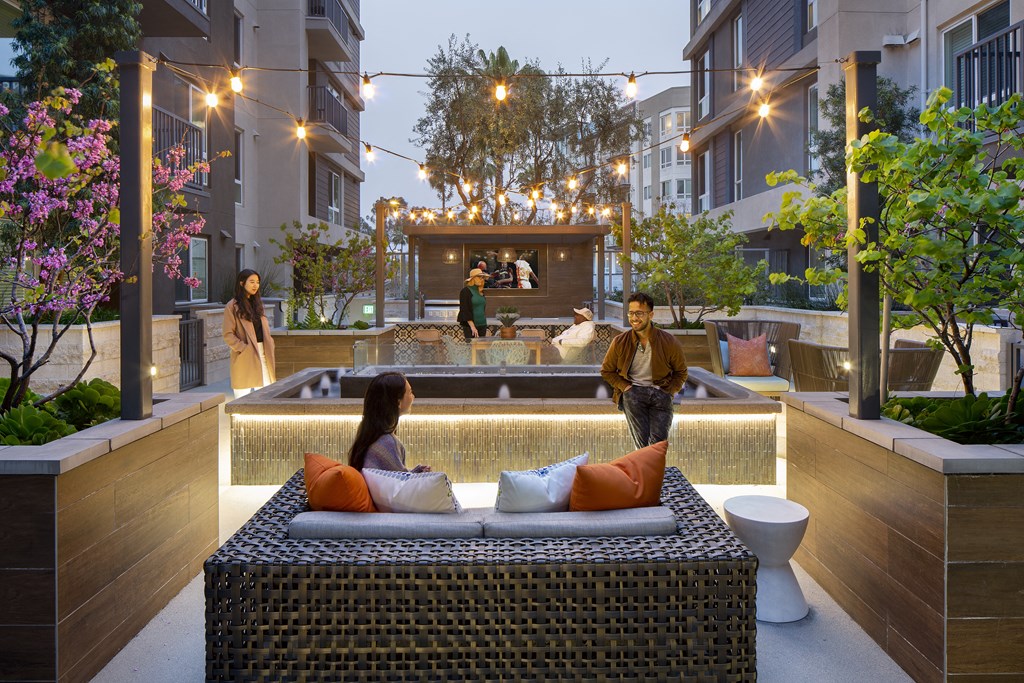 a couple sitting on a couch in front of a pool in an apartment complex