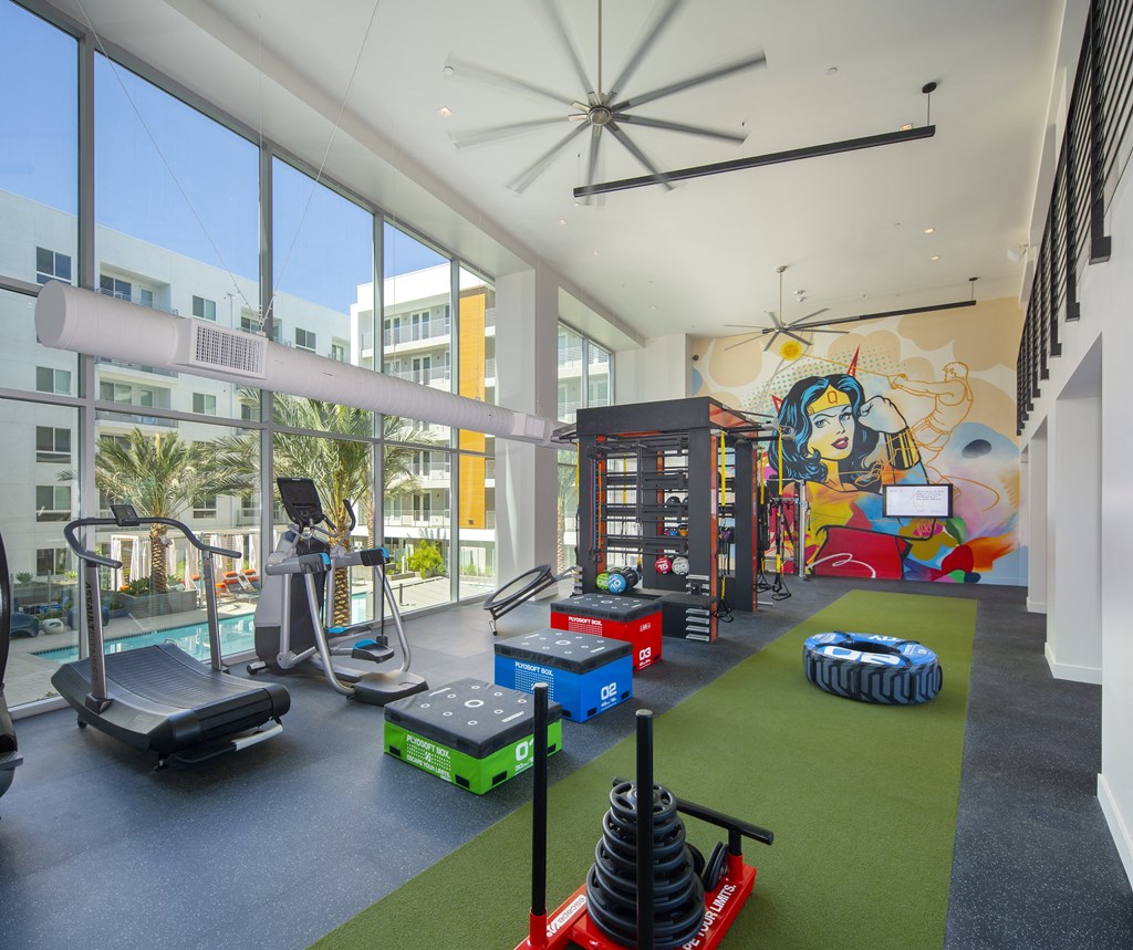 a gym with weights and other equipment and a mural on the wall