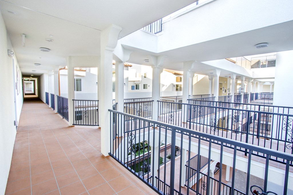 a hallway with tables and chairs in a building with white pillars