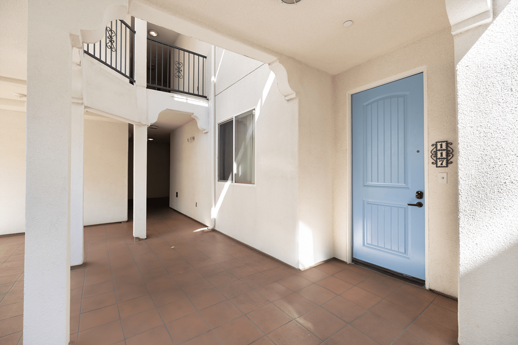 A blue door is on the right side of a white wall.