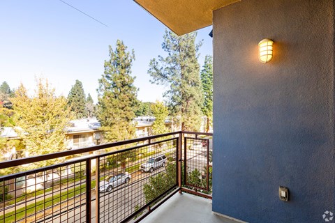 A balcony with a metal railing and a light on the wall.