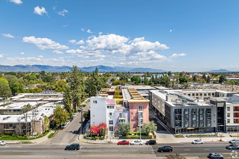 A city street with cars and buildings under a blue sky.