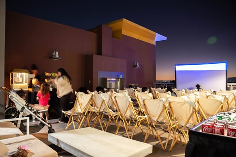 A movie theater with people sitting in the chairs and a screen in the background.