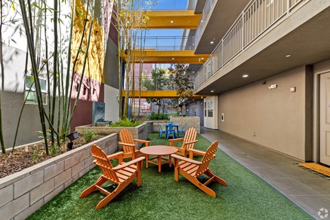 A patio with a table and chairs is surrounded by a wall and a tree.