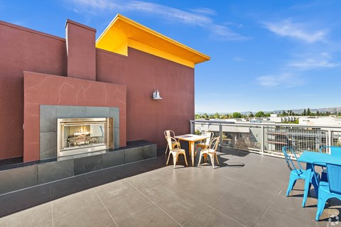 A patio with a table and chairs and a fireplace.