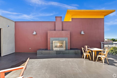 A modern patio with a fireplace and chairs.