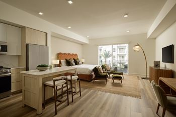 A modern kitchen with a breakfast bar and a living room with a couch and a chair.