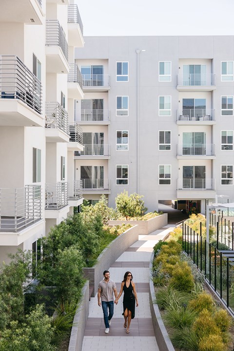 A man and a woman are walking down a path in front of a white building.