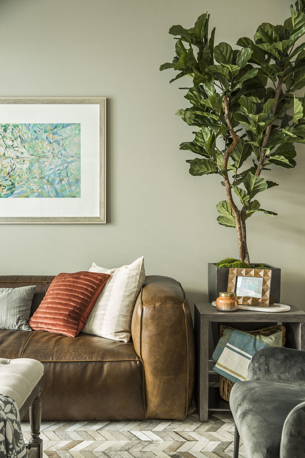 a living room with a brown leather couch and a potted plant