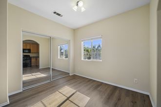 a bedroom with hardwood floors and beige walls at The Village Apartments, California, 91406