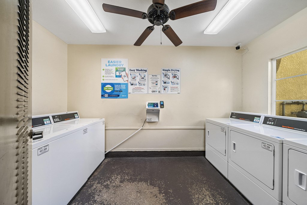a washer and dryer room with a ceiling fan at The Village Apartments, California