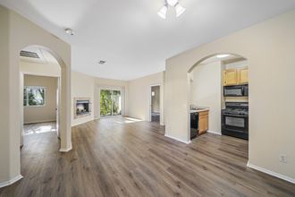 a living room and kitchen with hardwood floors and a fireplace at The Village Apartments, California