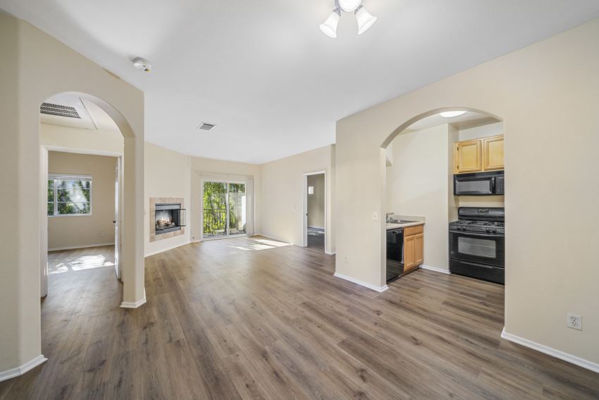 a living room and kitchen with hardwood floors and a fireplace at The Village Apartments, California