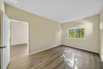 a bedroom with hardwood floors and beige walls at The Village Apartments, Van Nuys California