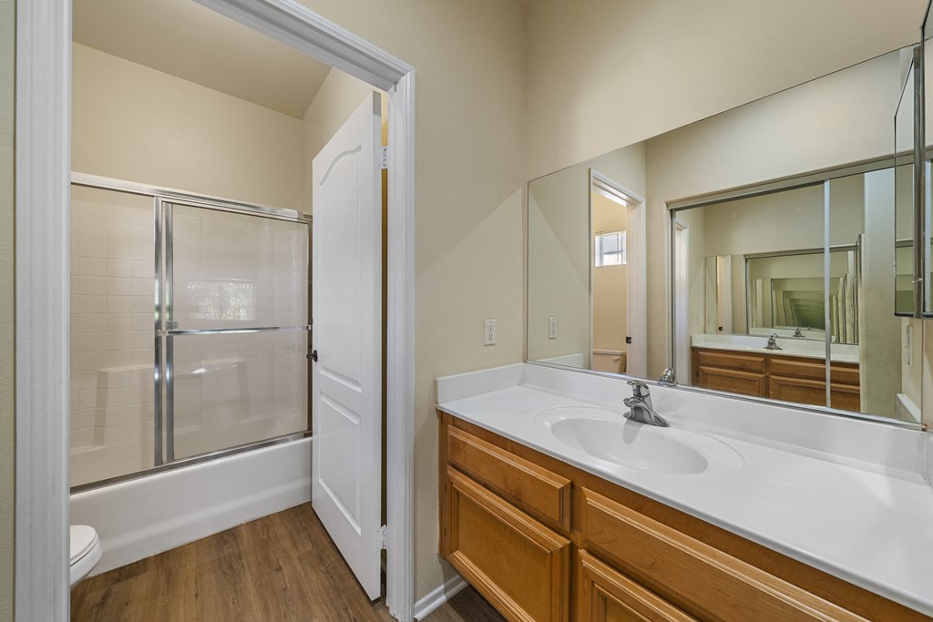 a bathroom with a large mirror and a large sink at The Village Apartments, Van Nuys, 91406