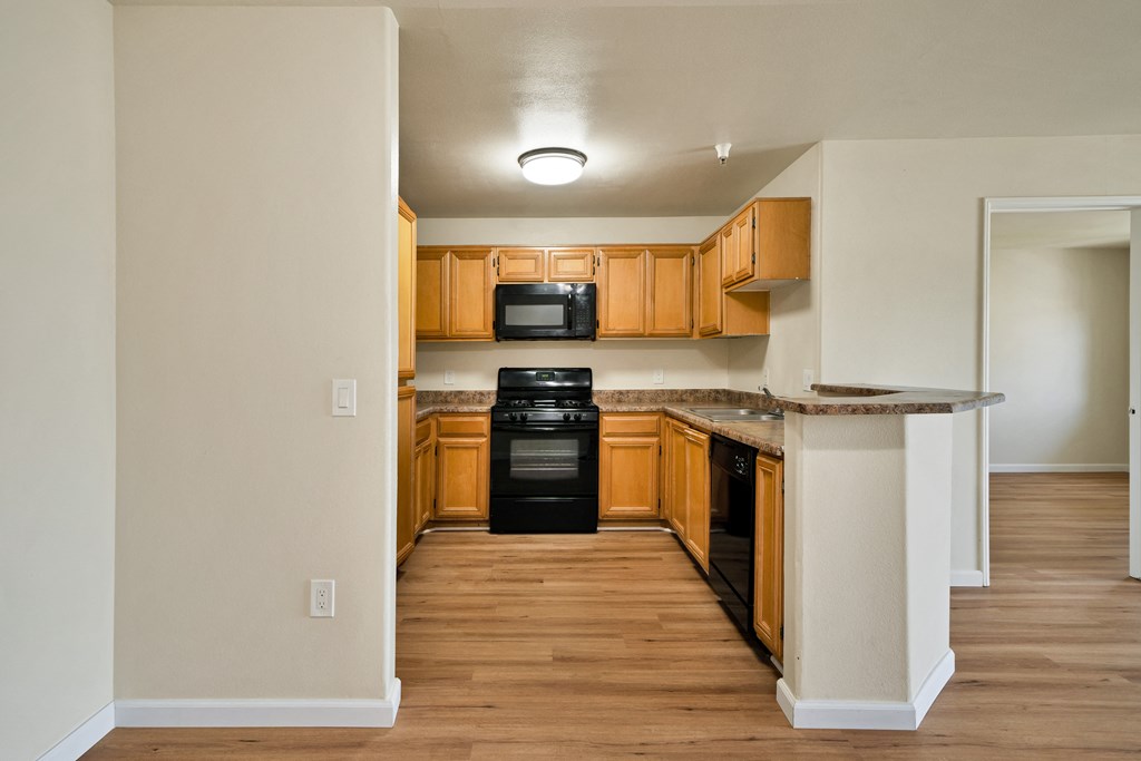an empty kitchen with wood flooring and black appliances