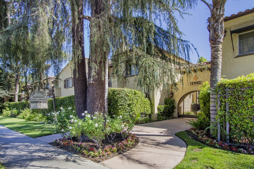 a sidewalk in front of a building with trees and flowers