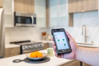 A person holding a smartphone with a green battery icon on the screen.