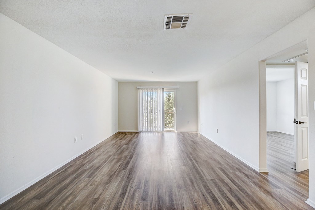 an empty living room with white walls and wood flooring