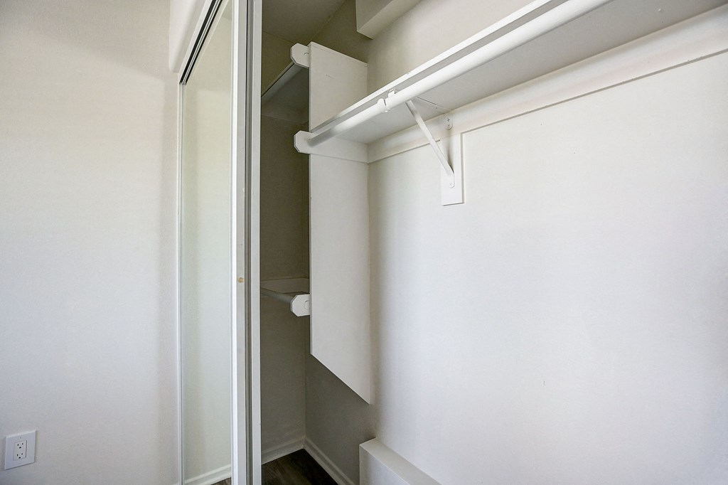 an empty closet with a white wall and a sliding glass door