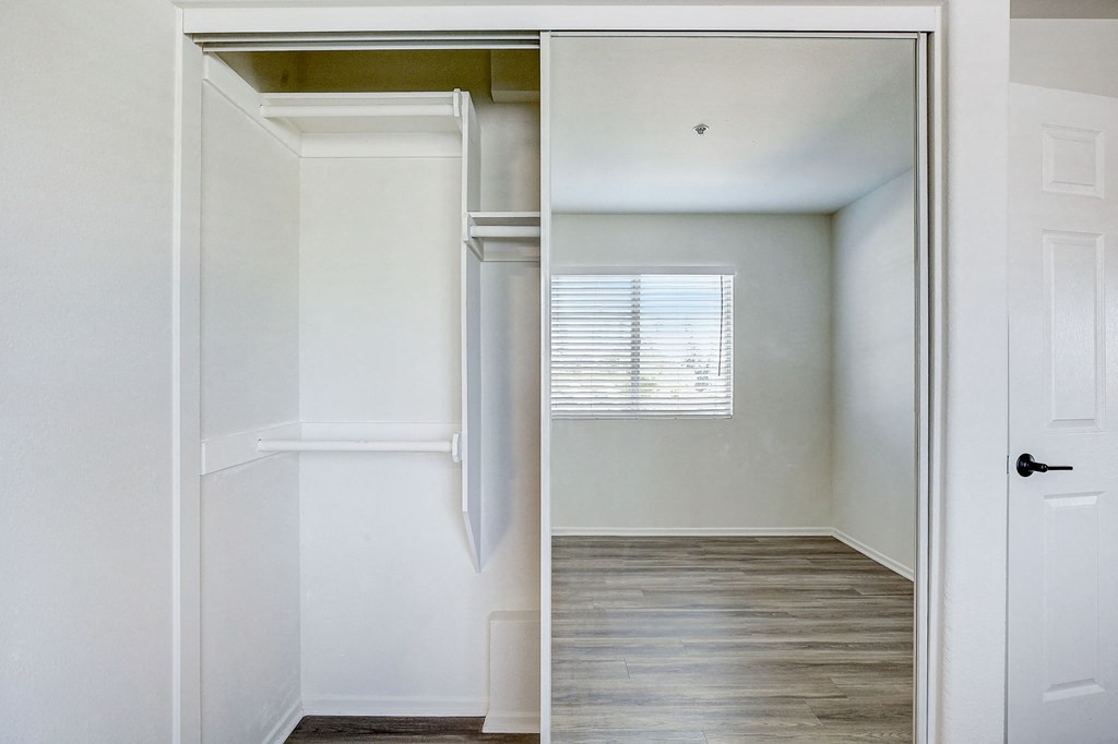 an empty bedroom with a closet and a window