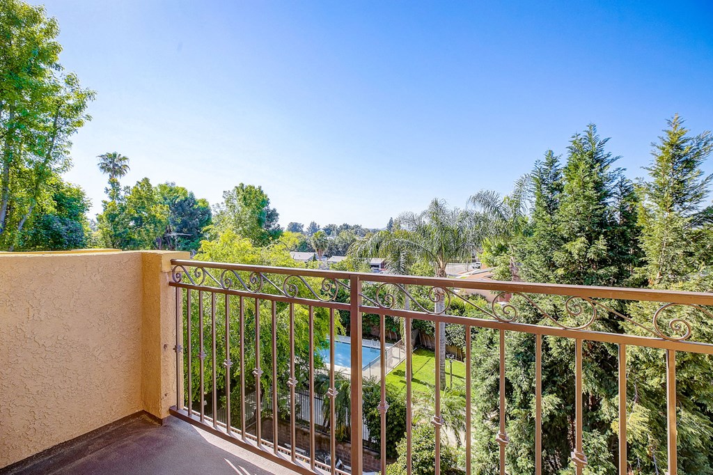 a balcony with a view of a pool and trees
