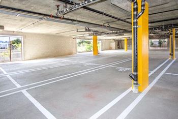 A parking garage with concrete floors and yellow poles.