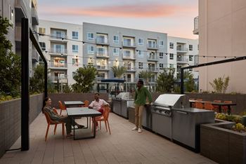 Two people are standing on a patio with a table and chairs.