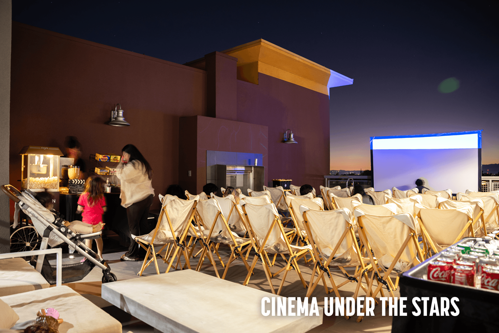 A group of people are sitting in chairs outside watching a movie under the stars.