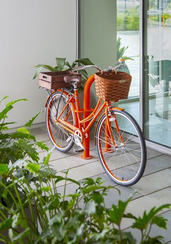 A bicycle with a basket is parked on a patio.